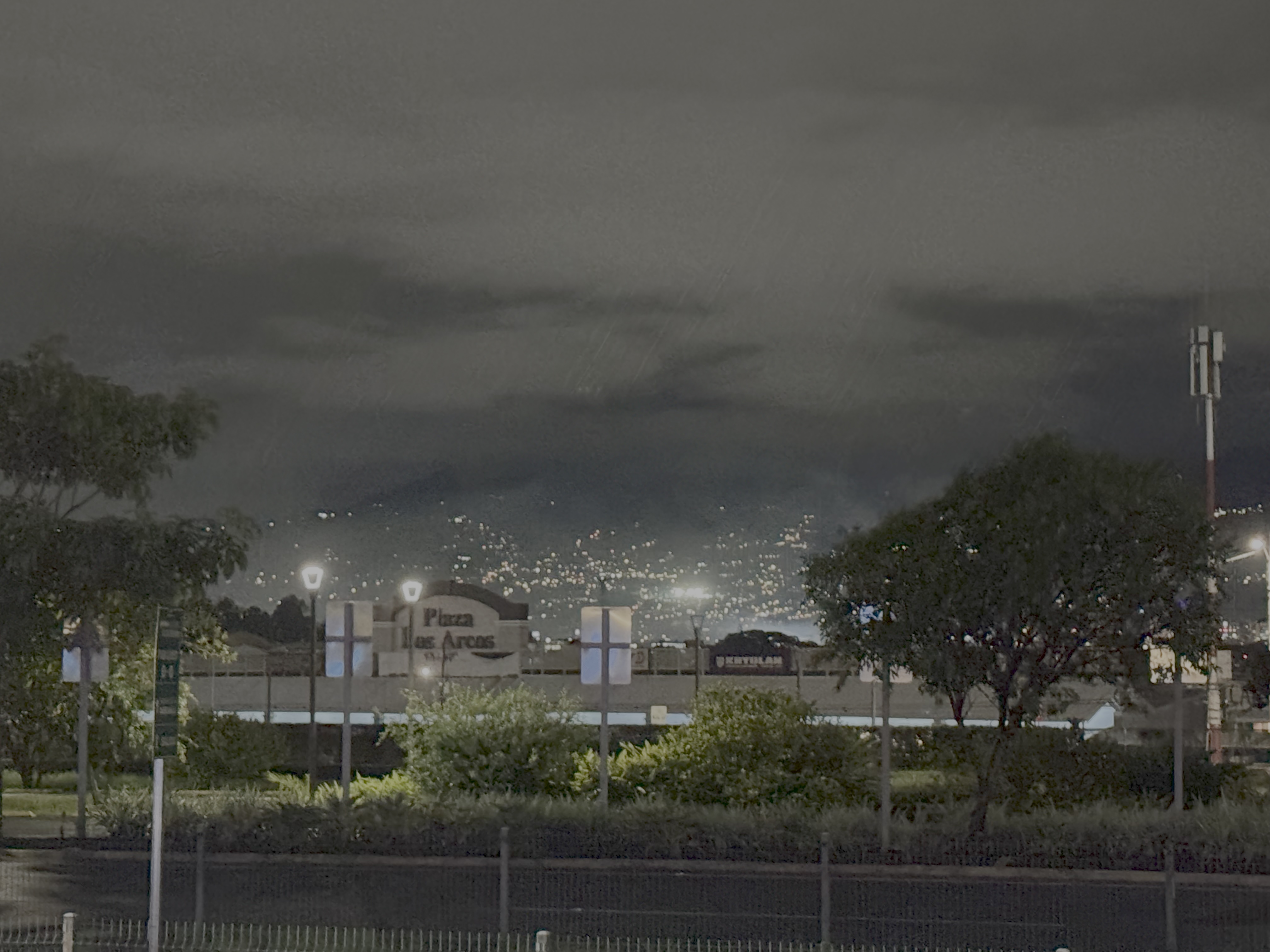 nighttime photo of far away city lights between large mountains; San Jose, Costa Rica